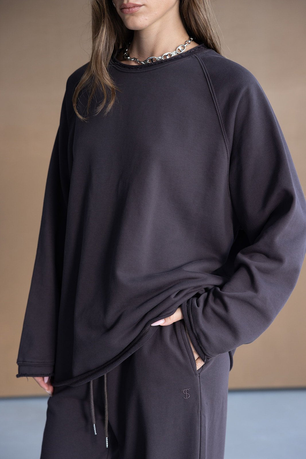 אישה לובשת סט טרנינג אופנתי בצבע כהה עם שרשרת כסף, בגדי נשים נוחים ליום יום