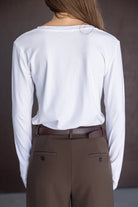 חולצת נשים לבנה עם שרוולים ארוכים ומכנסיים חומים מחויטים, מראה אופנתי קלאסי