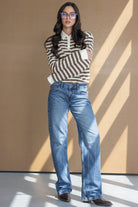 אישה עם משקפיים לובשת חולצה פסים ארוכה ומכנסי ג'ינס רחבים, לוק אופנתי לנשים