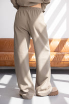 מכנסיים רחבים לנשים בצבע בז' עם מותן גמישה, צילום באור טבעי ליד ספה חומה