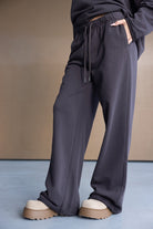 מכנסי טרנינג נשים רחבים בצבע כהה עם שרוך גומי, נעלי טרנד עבות, אופנת רחוב מודרנית