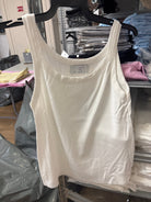 גופיה לבנה לנשים עם כתפיות רחבות על קולב, רקע מדפי בגדים בחנות אופנה