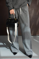 מכנסיים רחבים לנשים אפור עם שרוך לבן, סוודר כהה ותיק צד שחור אופנתי