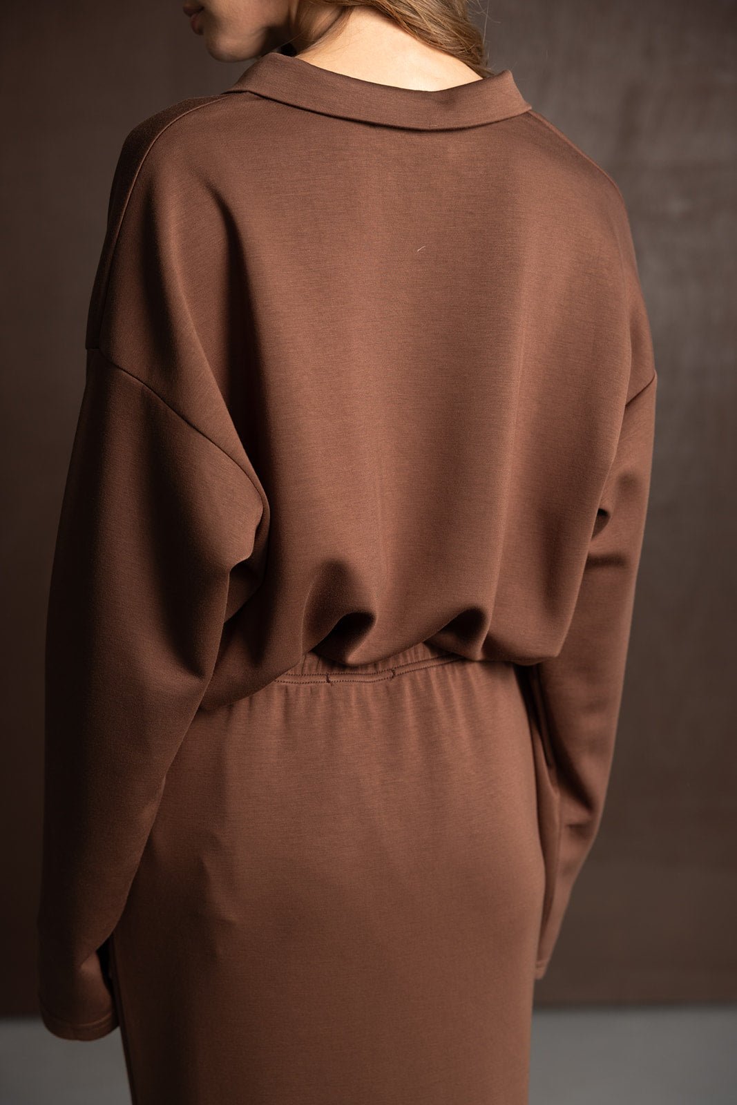 אישה לובשת שמלת מيدي חומה עם שרוולים ארוכים אופנתית, מבט מאחור, טרנד 2024