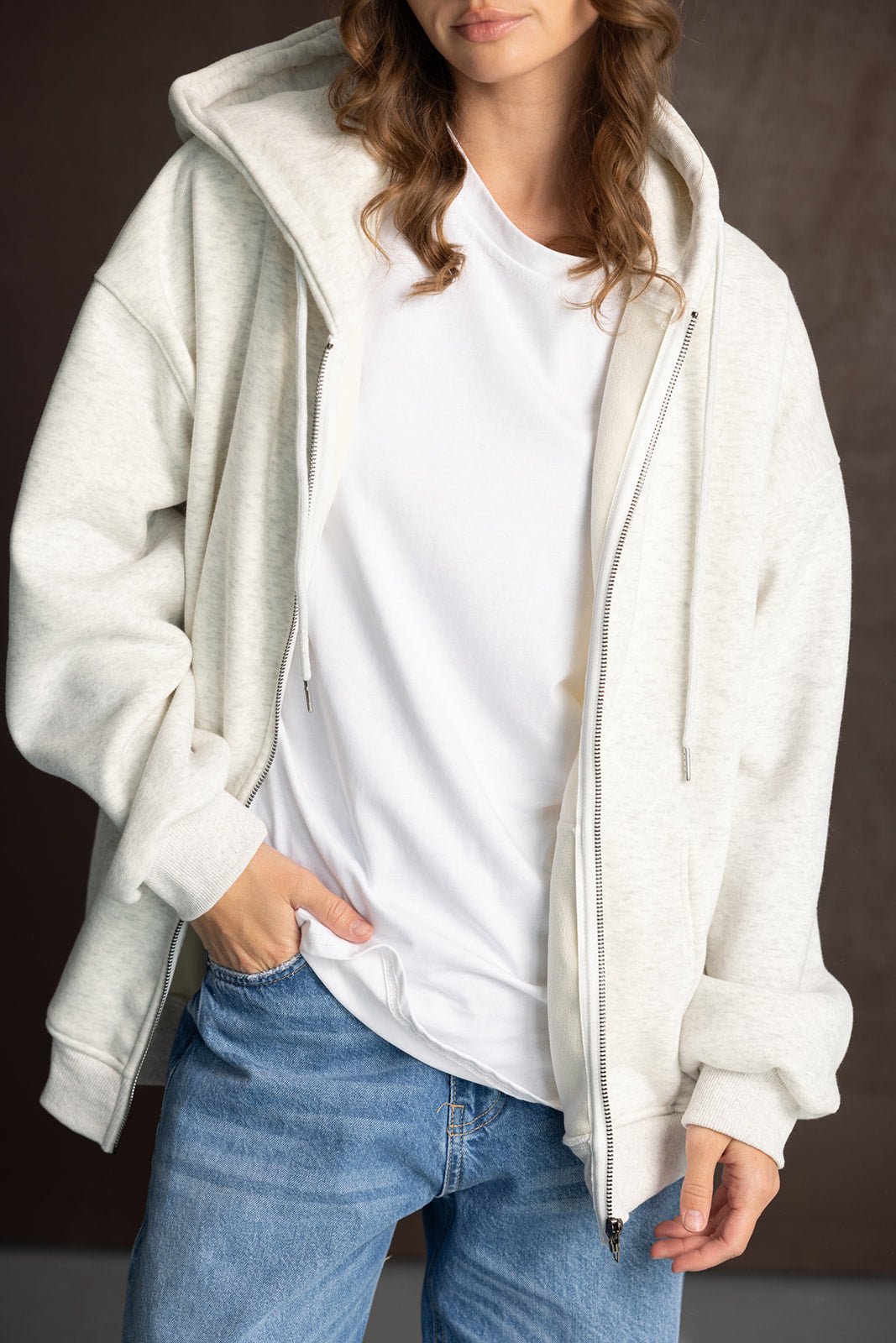 אישה עם סווטשירט קפוצ'ון אפור בהיר, חולצה לבנה וג'ינס, אופנת רחוב לנשים