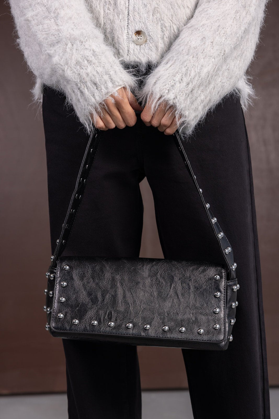 תיק צד שחור לנשים עם ניטים כסופים, ג'קט פרוותי לבן ומכנס שחור אופנתי