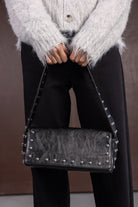 תיק צד שחור לנשים עם ניטים כסופים, ג'קט פרוותי לבן ומכנס שחור אופנתי