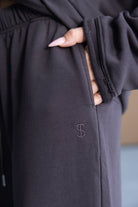 מכנסי טרנינג נשים אפור כהה עם כיס פתוח ודיטייל רקום, ציפורניים ארוכות מודגשות