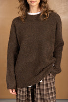 דוגמנית לובשת סוודר חום צמרירי וחצאית משבצות חומה, אופנת נשים חורף