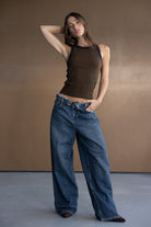 דוגמנית לובשת גופיית נשים חומה עם שוליים כהים ומכנסי ג'ינס רחבים, סטייל קז'ואל אופנתי לנשים צעירות