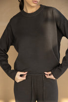 אישה לובשת סט טרנינג נשים בצבע שחור, חולצה ארוכה ומכנסיים, אופנה נוחה ויומיומית