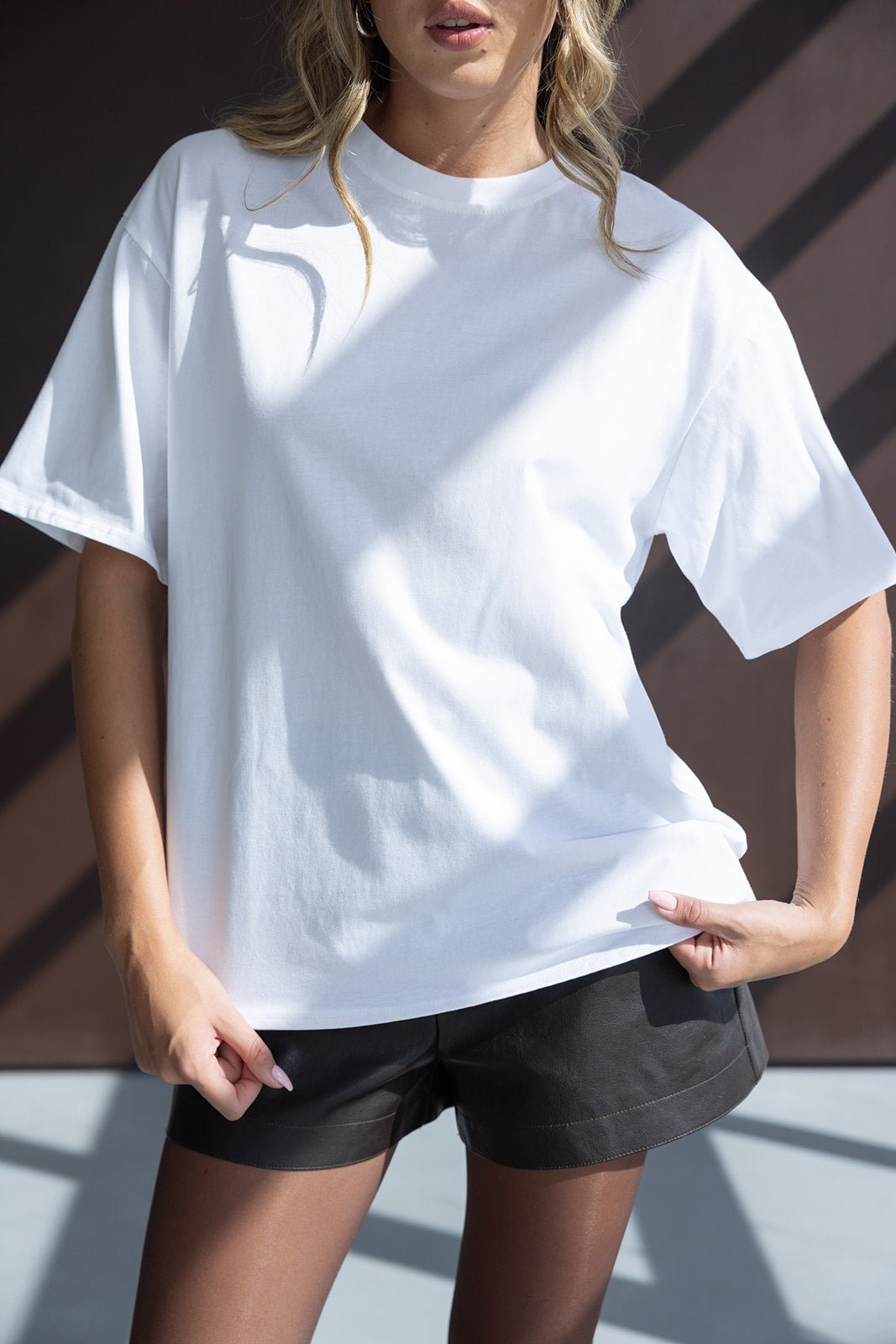 אישה לובשת טי שירט לבנה ומכנסיים קצרים שחורים, אופנת קיץ לנשים