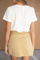 חצאית קצרה בז׳ עם כיסים אחוריים, טי שירט לבנה, אופנת נשים קיץ