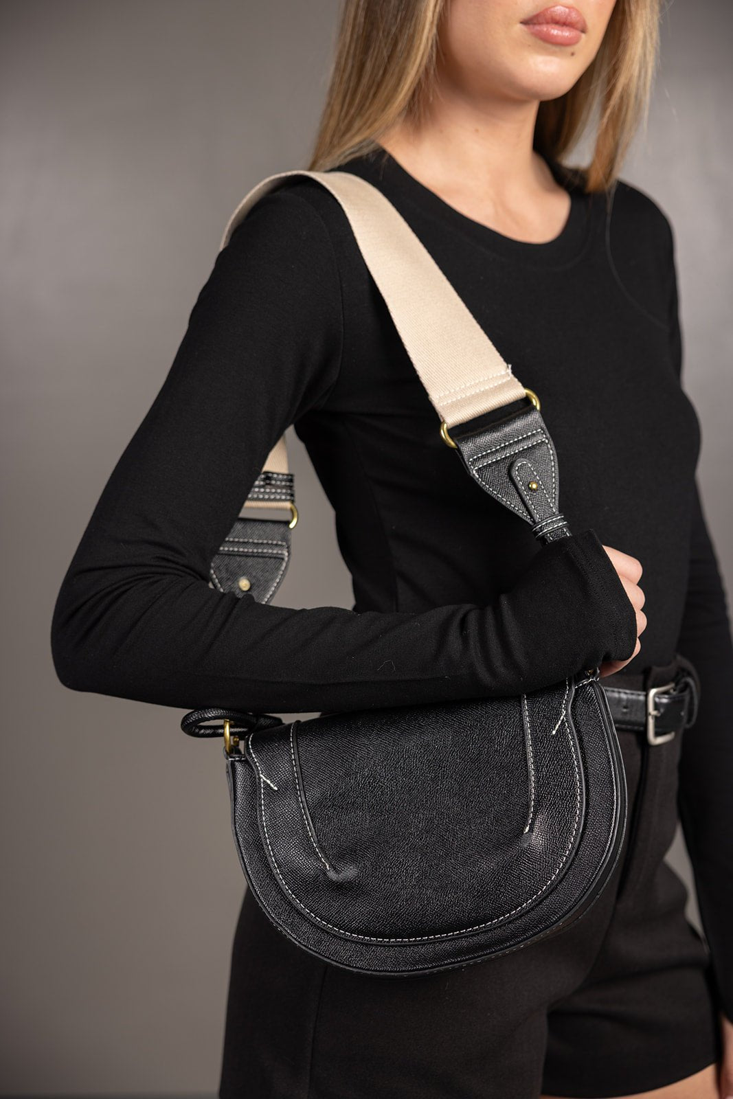 אישה עם חולצה שחורה תיק צד שחור עם רצועה עבה אופנה לנשים