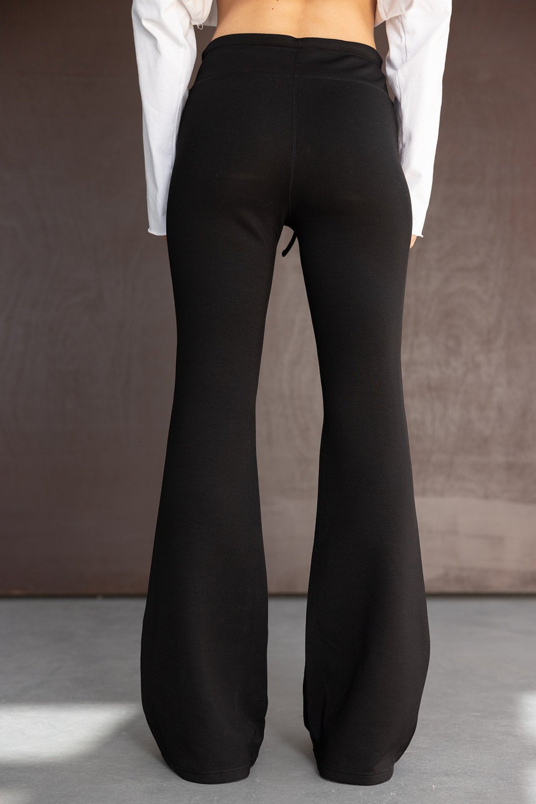 מכנסי נשים שחורים בגזרה מתרחבת, מבד נוח, צילום מאחור על דוגמנית צעירה