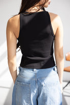 אישה לובשת גופיה שחורה מכותנה בגזרה צמודה עם מכנסי ג'ינס גבוהים רחבים, אופנת קיץ לנשים