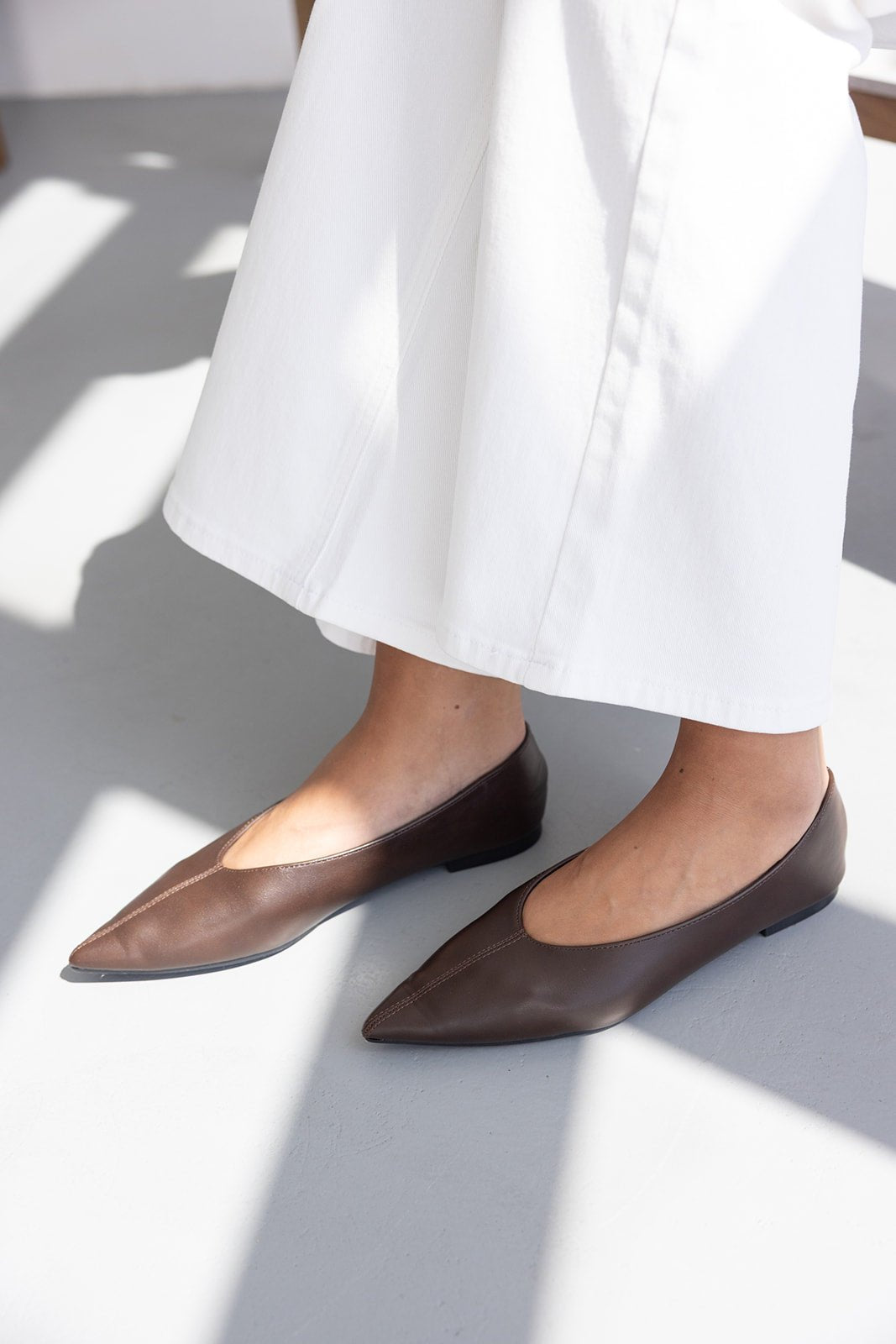 נעליים שטוחות חומות לנשים עם חוד שפיץ, נלבשות עם מכנסיים לבנים, אופנת קיץ לנשים