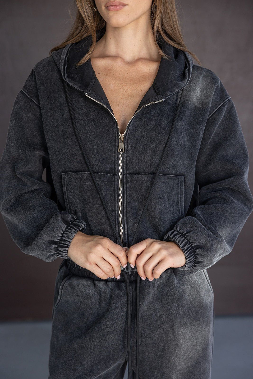 אישה לובשת סרבל ג'ינס כהה עם רוכסן וכובע קפוצ'ון, אופנת נשים צעירה וטרנדית