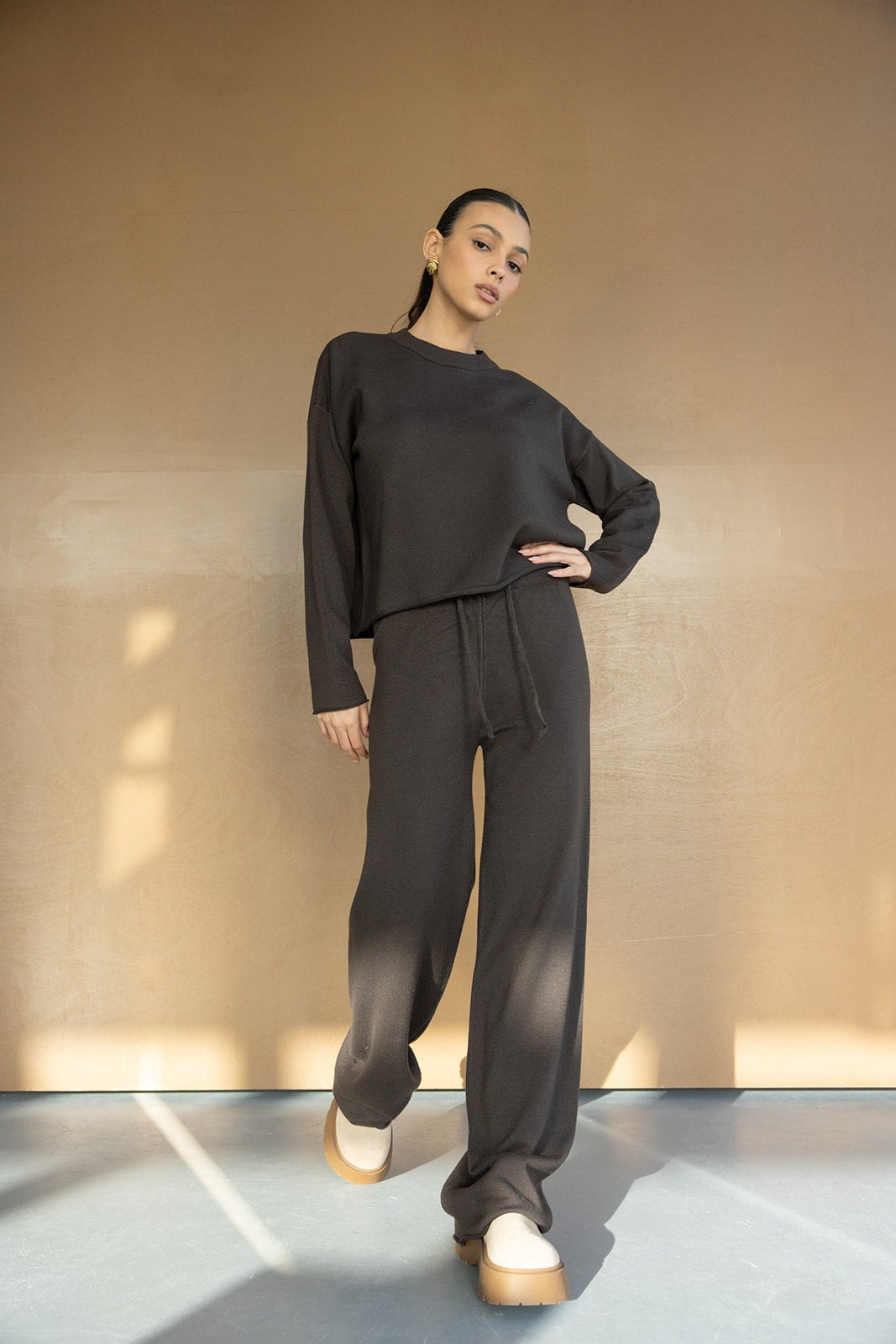 דוגמנית לובשת סט טרנינג נשים רחב בצבע שחור עם מגפיים בהירים, אופנת נשים צעירה ועדכנית