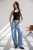 דוגמנית לובשת גופיית טופ שחורה ומכנסי ג'ינס רחבים בגזרה גבוהה, אופנת נשים טרנדית