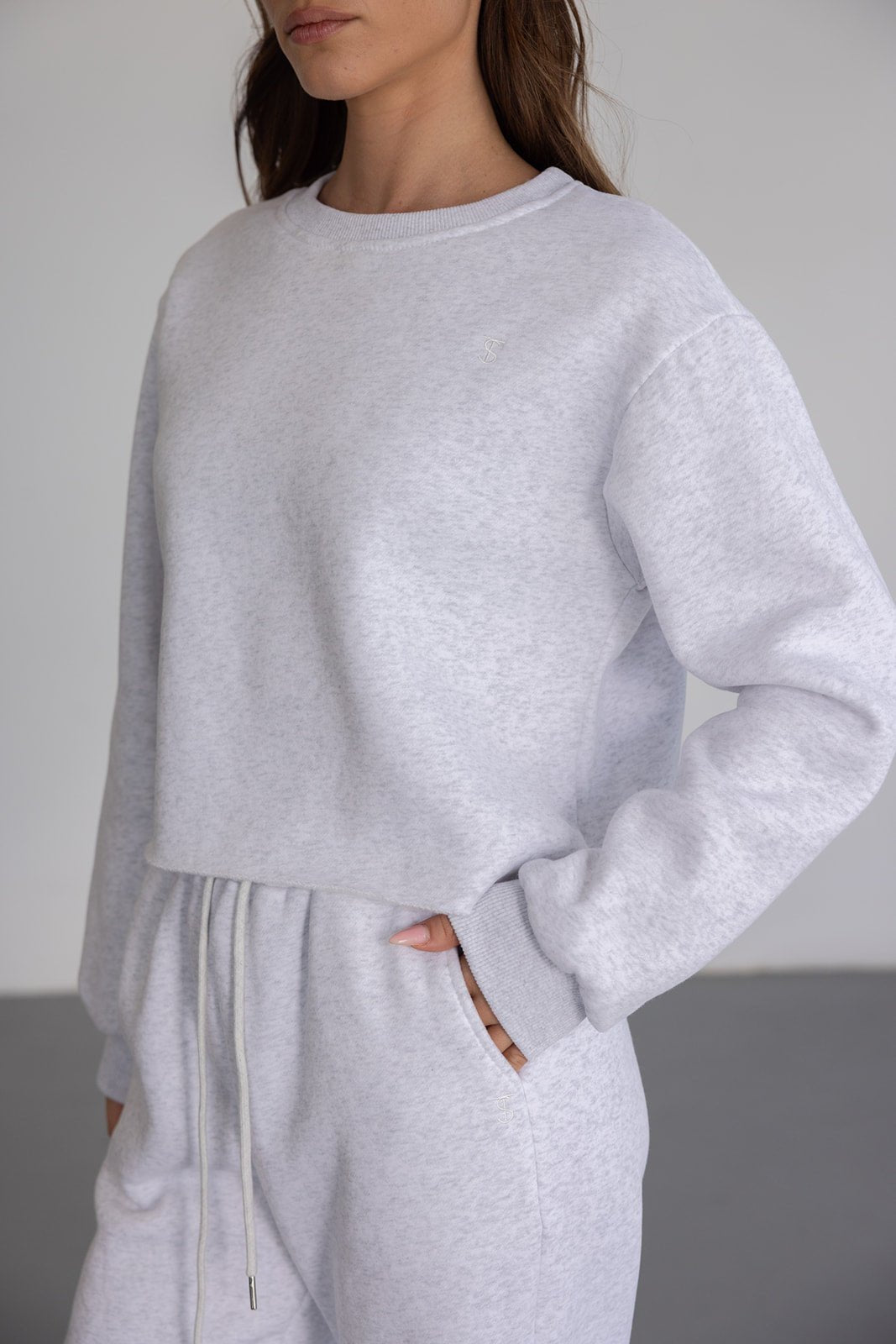 אישה לובשת סט טרנינג אפור בהיר, סווטשירט ומכנסיים עם שרוך, אופנת נשים מודרנית