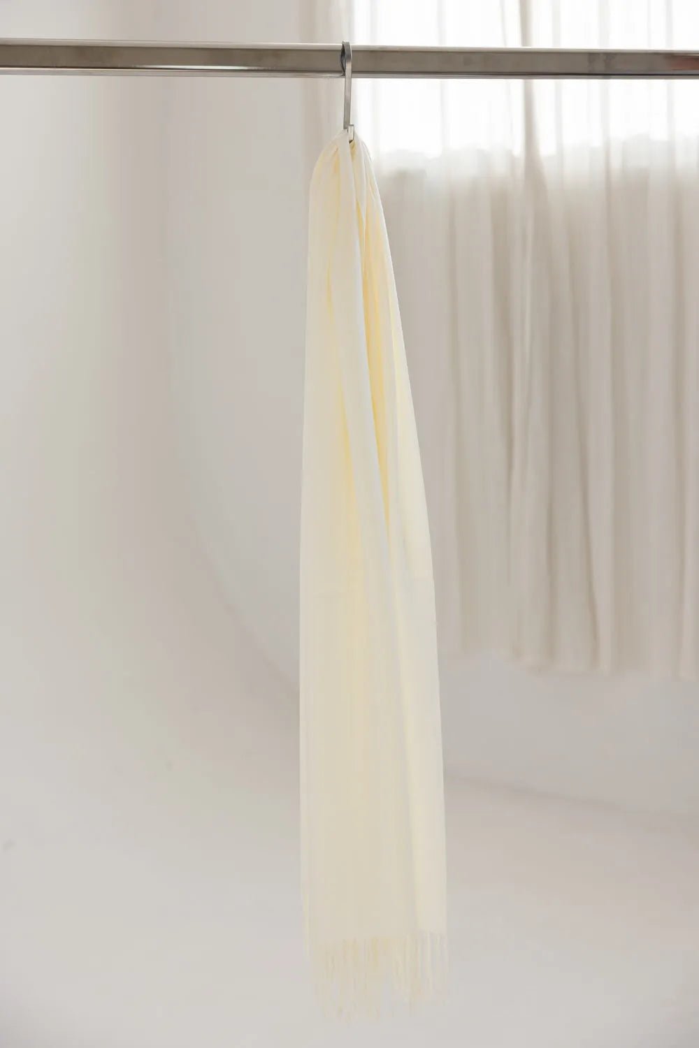 צעיף קרם לנשים תלוי על מקל תליה, רקע בהיר, עיצוב אלגנטי, אקססוריז אופנה