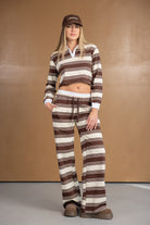 דוגמנית לובשת סט פסים חום-שמנת קז'ואל, חולצה ארוכה ומכנסיים מחויטים לנשים.