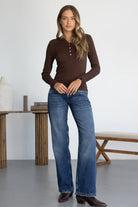 דוגמנית לובשת ג'ינס בגזרה ישרה וחולצת כפתורים חומה בסגנון קז'ואל לנשים