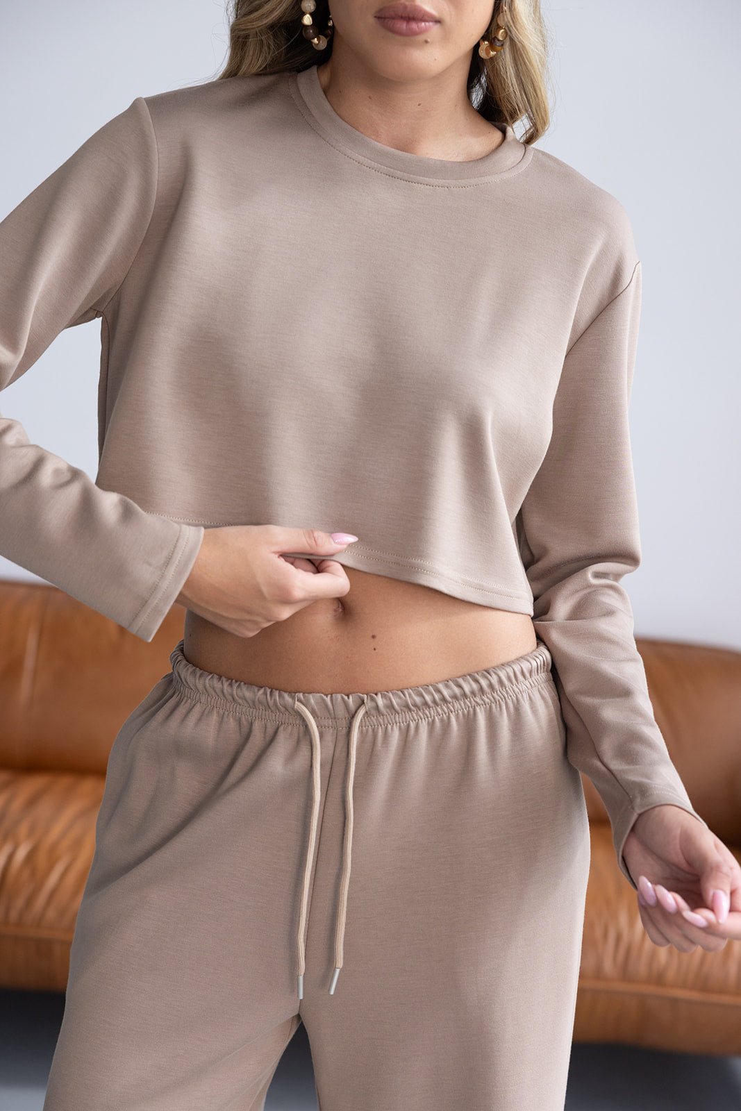 אישה לובשת סט טרנינג בגוון בז', סווטשירט קצר ומכנסיים בגומי, אופנה לנשים