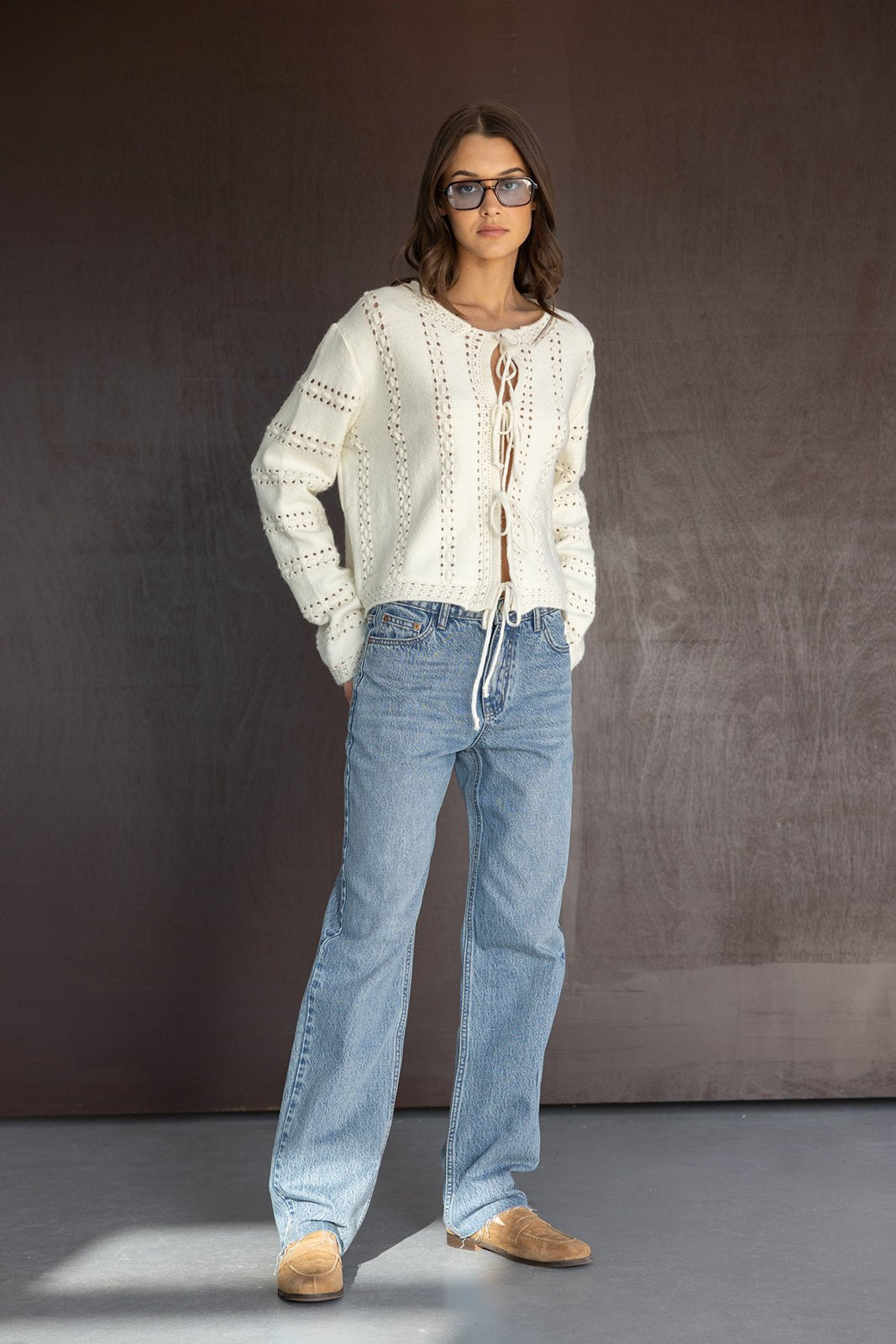 דוגמנית עם סוודר לבן קשירה, ג׳ינס רחב ומשקפי שמש, אופנת נשים צעירה