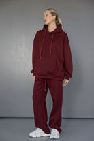 דוגמנית לובשת סט קז'ואל לנשים בצבע בורדו עם קפוצ'ון ומכנסיים רחבים, מצולמת בסטודיו