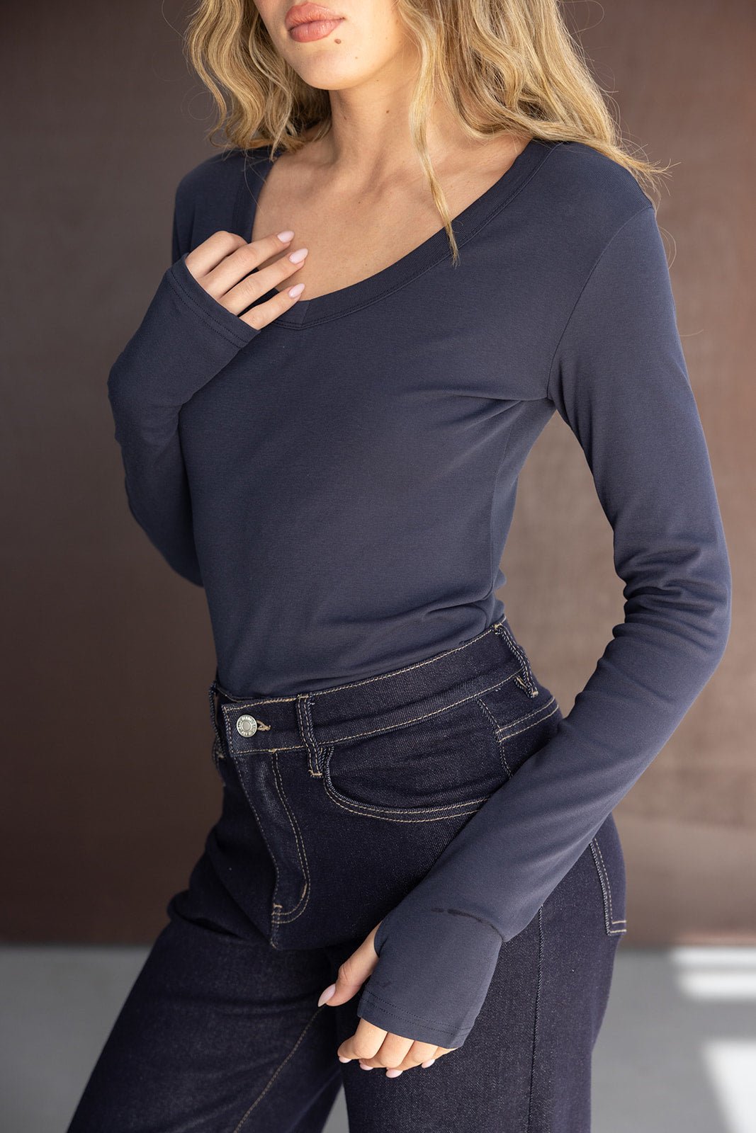 דוגמנית עם חולצת שרוול ארוך כחולה ומכנסי ג'ינס כהים, אופנת נשים עדכנית