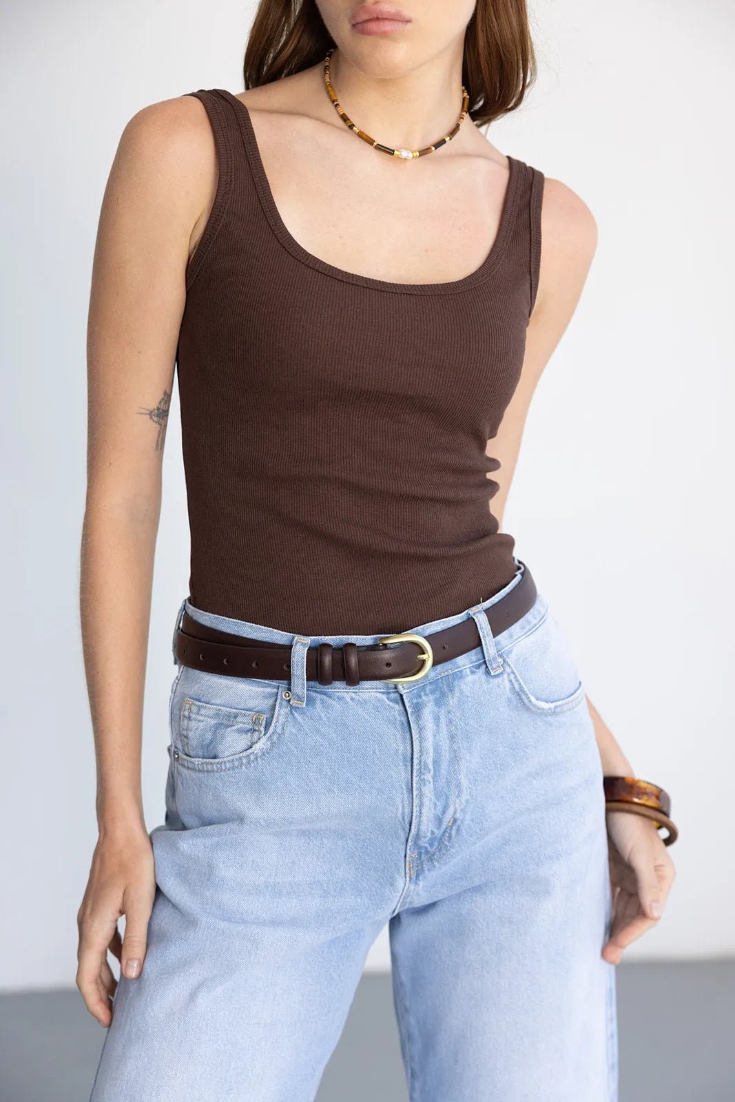 גופיה חומה לנשים עם צווארון מרובע, ג'ינס כחול בגזרה גבוהה, חגורה חומה ושרשרת טרנדי