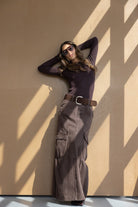 דוגמנית עם סקיני כהה, חצאית ארוכה עם חגורה, משקפי שמש, אופנת נשים עדכנית