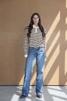 אישה עם חולצת פסים חומה ולבנה, ג'ינס ישר ומשקפי שמש, אופנת נשים צעירה