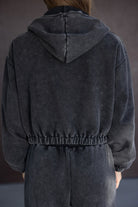 אישה לובשת סט טרנינג קפוצ'ון אפור כהה מבד רך, מבט מאחור, אופנת נשים צעירה