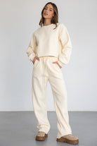 דוגמנית לובשת סט טרנינג נשים בצבע שמנת עם נעליים חומות, אופנה קז'ואל לנשים