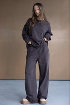 דוגמנית לובשת סט טרנינג רחב לנשים בצבע כהה, חולצה ומכנסיים תואמים, אופנה לנערות