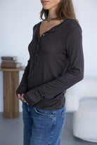 אישה לובשת חולצת כפתורים ארוכה בצבע שחור ומכנסי ג'ינס, אופנת נשים עדכנית