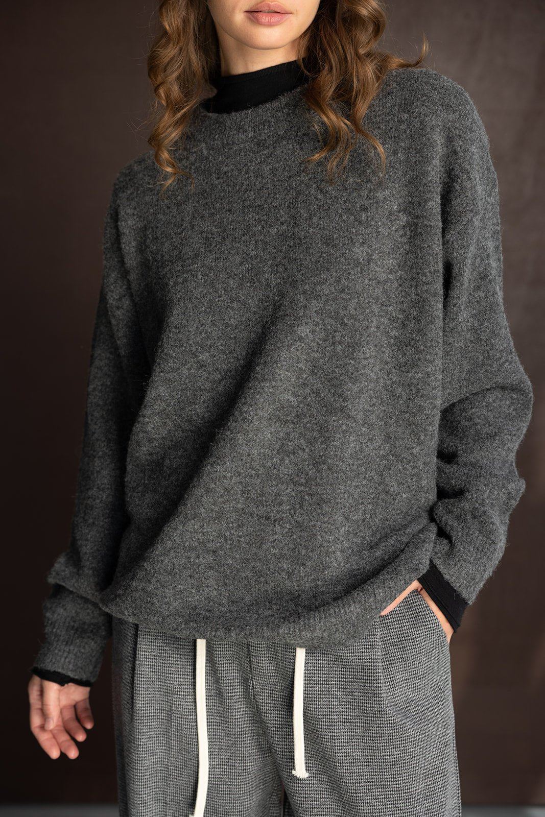 דוגמנית לובשת סוודר אפור עם צווארון גבוה ומכנסי טרנינג משובצים, אופנת חורף לנשים