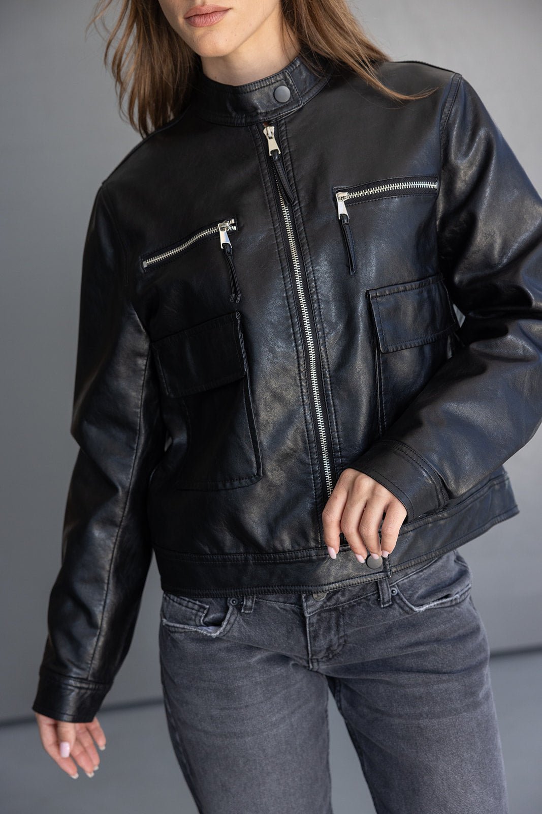 אישה עם ג'קט עור שחור אופנתי עם רוכסנים ופאצ'ים משולב עם ג'ינס כהה לוק חורפי לנשים