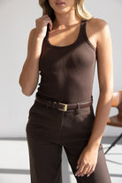 אישה לובשת גופיה חומה ומכנס מחויט חום עם חגורה חומה, אופנת נשים קלאסית