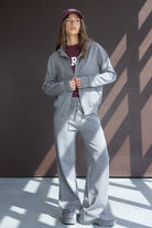 אישה לובשת סט טרנינג אפור אופנתי עם קפוצ׳ון, כובע מצחייה ובגדי קז'ואל לנשים