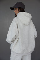 אישה צעירה עם קפוצ'ון אפור וכובע מצחייה שחור, לוק ספורטיבי אופנתי לנשים