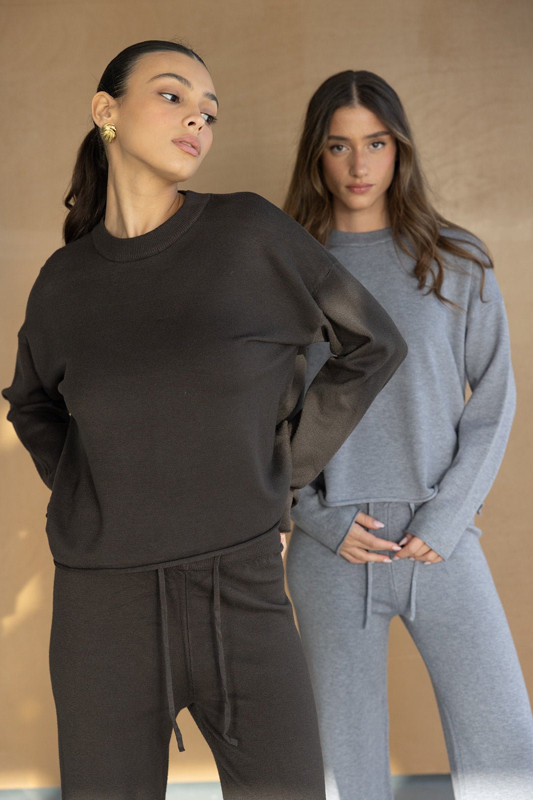 שתי דוגמניות לובשות טרנינג נשי אופנתי, אחת בסט חום והשנייה בסט אפור, רקע ניטרלי