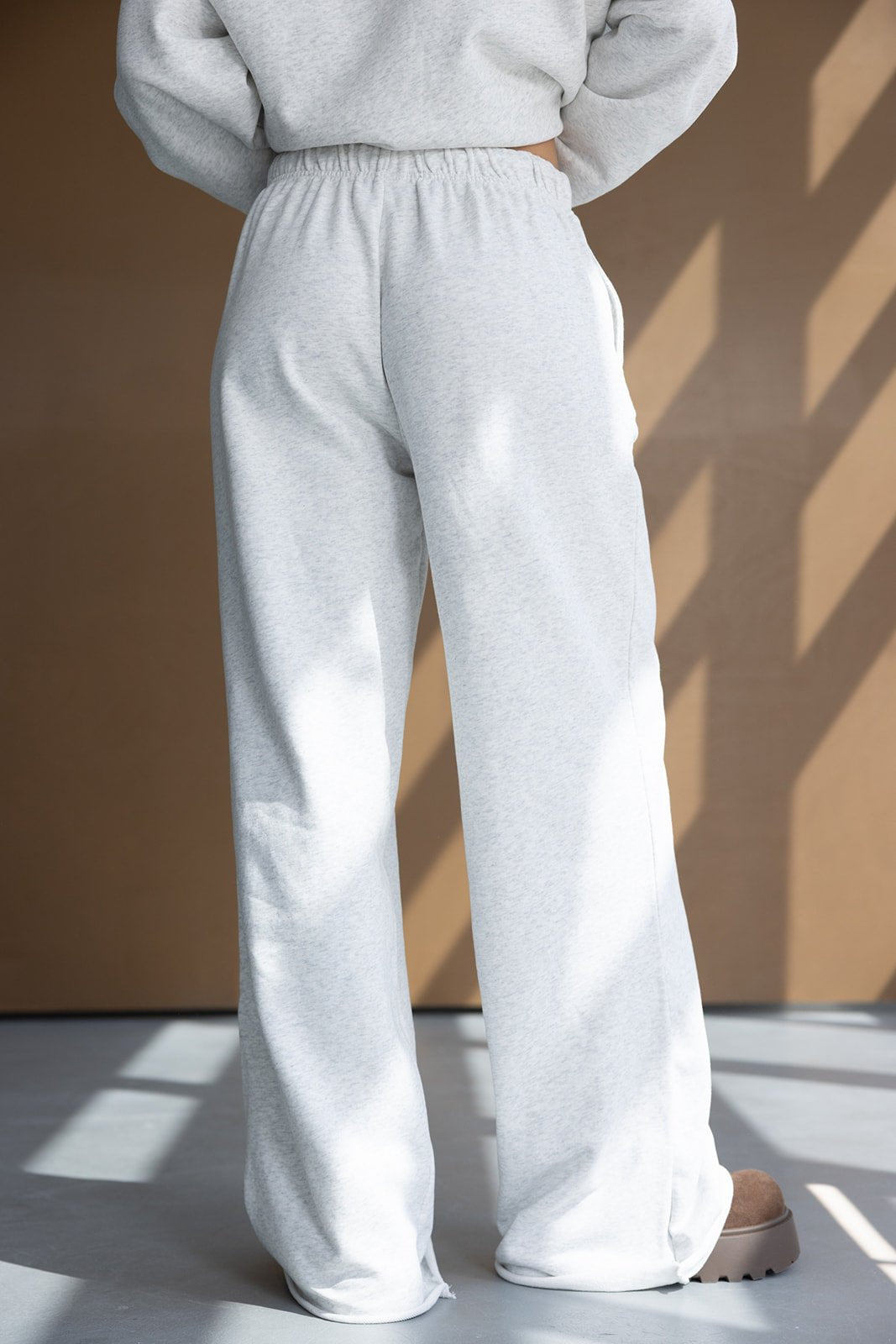 מכנסי טרנינג לנשים בצבע אפור בהיר, גזרה רחבה, בד נעים, צילום מאחור באור טבעי