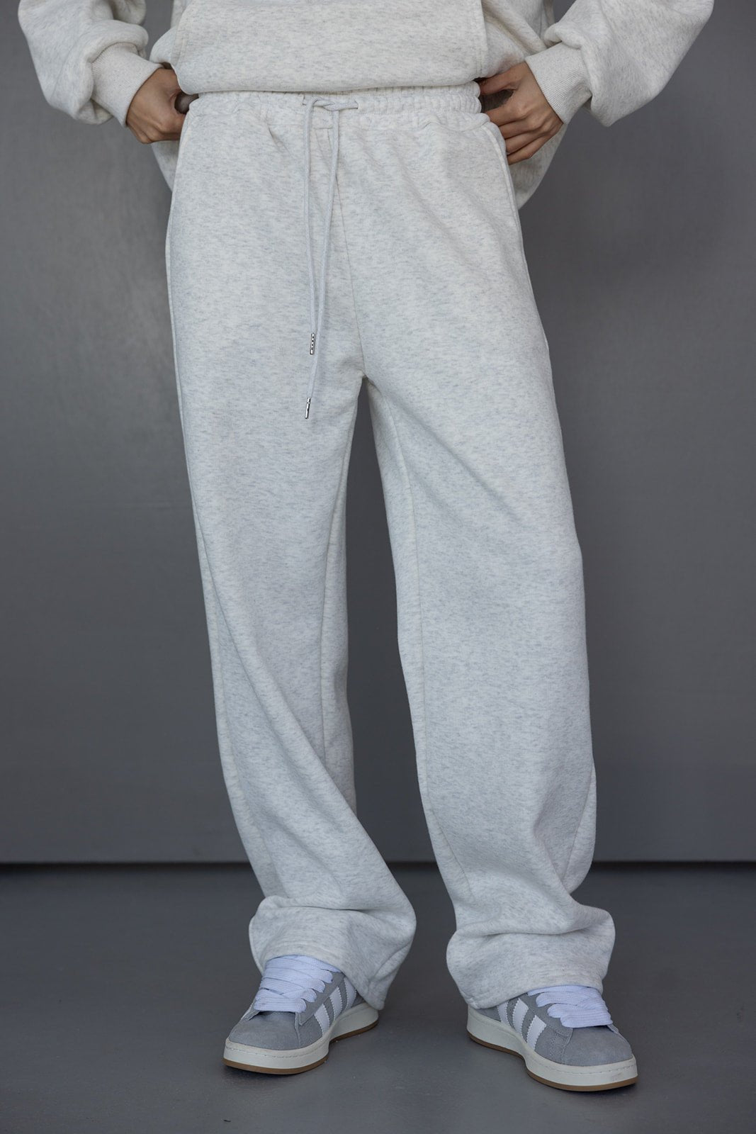 מכנסי טרנינג נשים אפור בהיר בגזרה רחבה עם שרוך וסניקרס אפורות אופנתיות