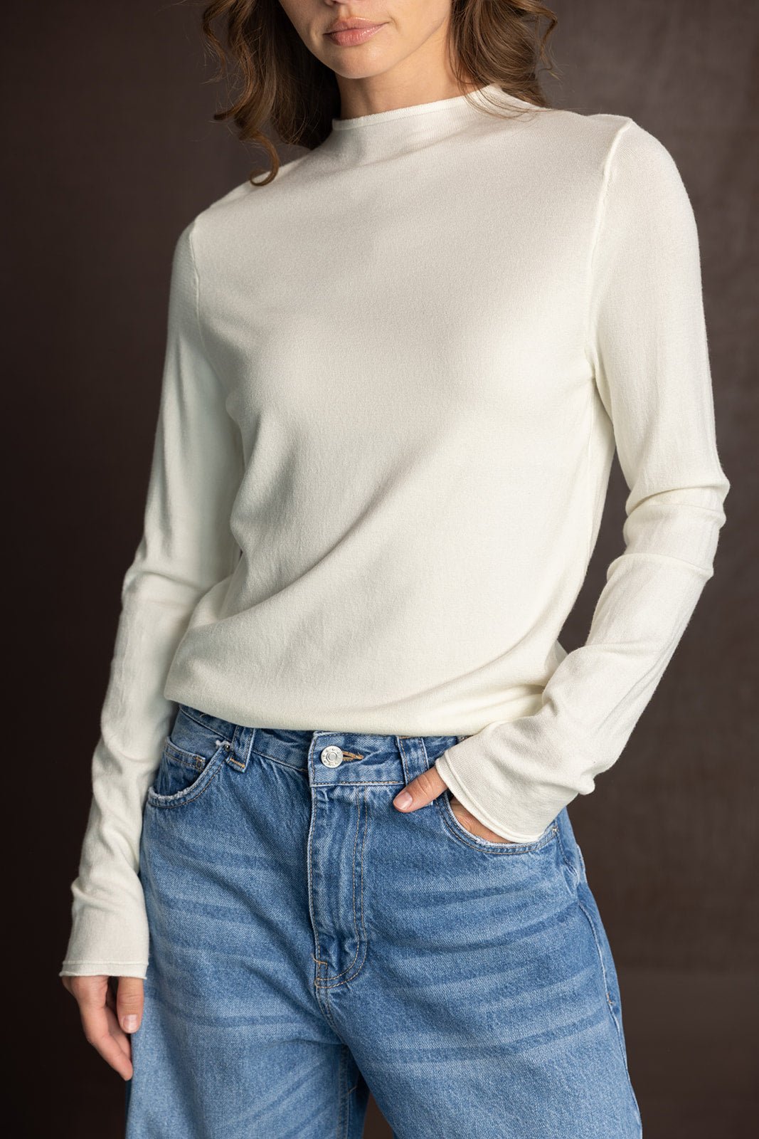 אישה עם חולצה לבנה עם שרוולים ארוכים ומכנסי ג'ינס בגזרה גבוהה, אופנת נשים עכשווית