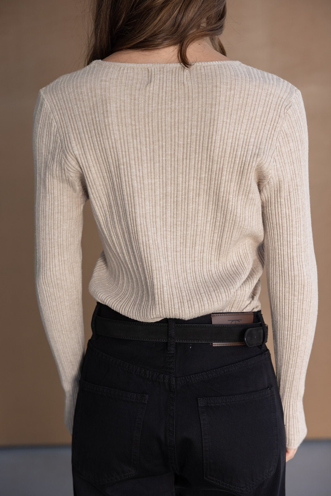 חולצת סריג בז' לנשים עם שרוולים ארוכים ומכנסי ג'ינס שחורים, צילום מאחור