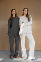 שתי נשים לובשות סטים סריג נוחים, אחת באפור כהה ואחת באפור בהיר, אופנת נשים חורף